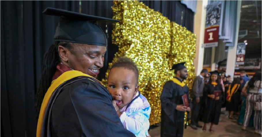 parent holding their child at college graduation ceremony